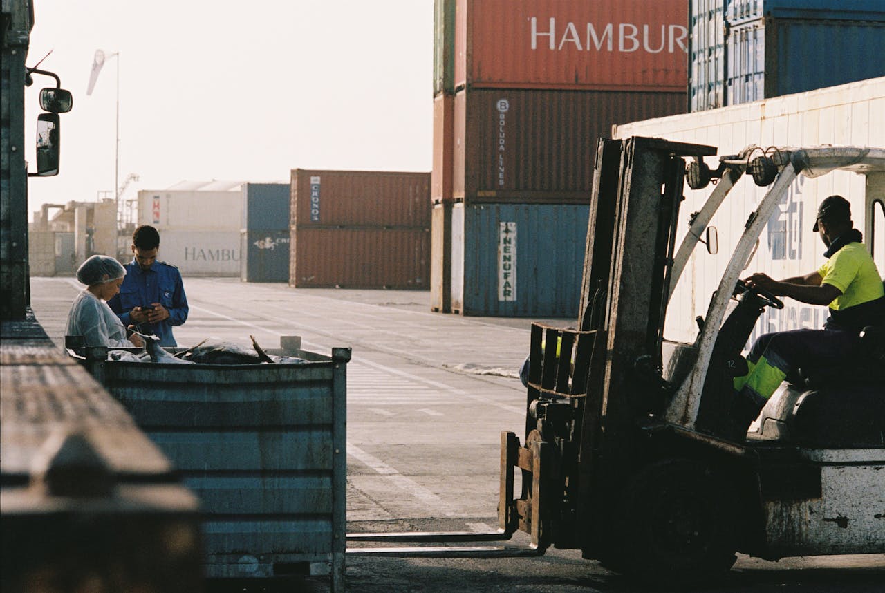services-03 Workers operating a forklift in a shipping container yard at Praia port, Cabo Verde.