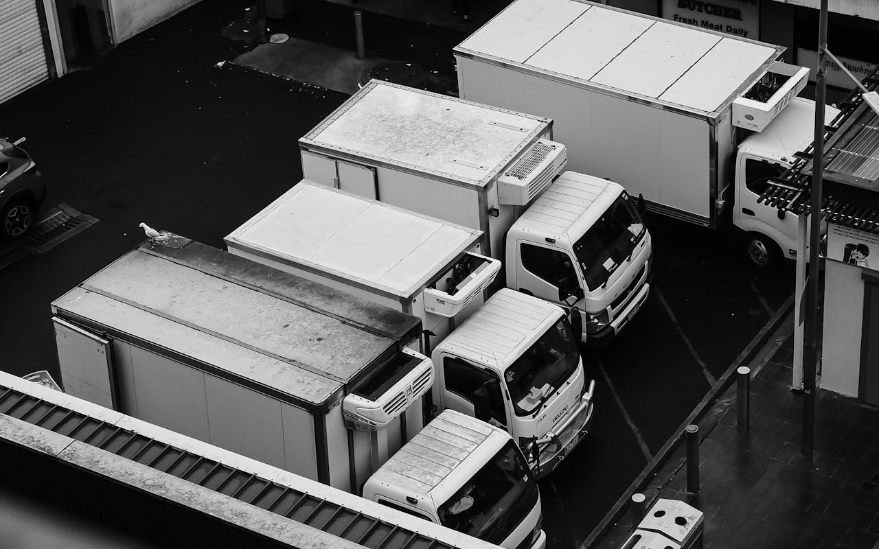 services-01 Monochrome aerial shot of commercial trucks parked in a lot, emphasizing industrial design.